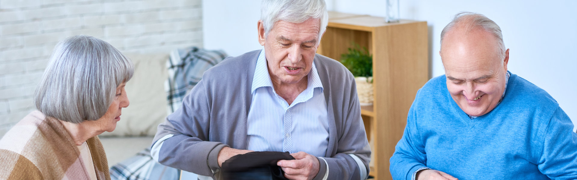 Portrait of senior people playing lotto game sitting at glass table in living room of retirement home