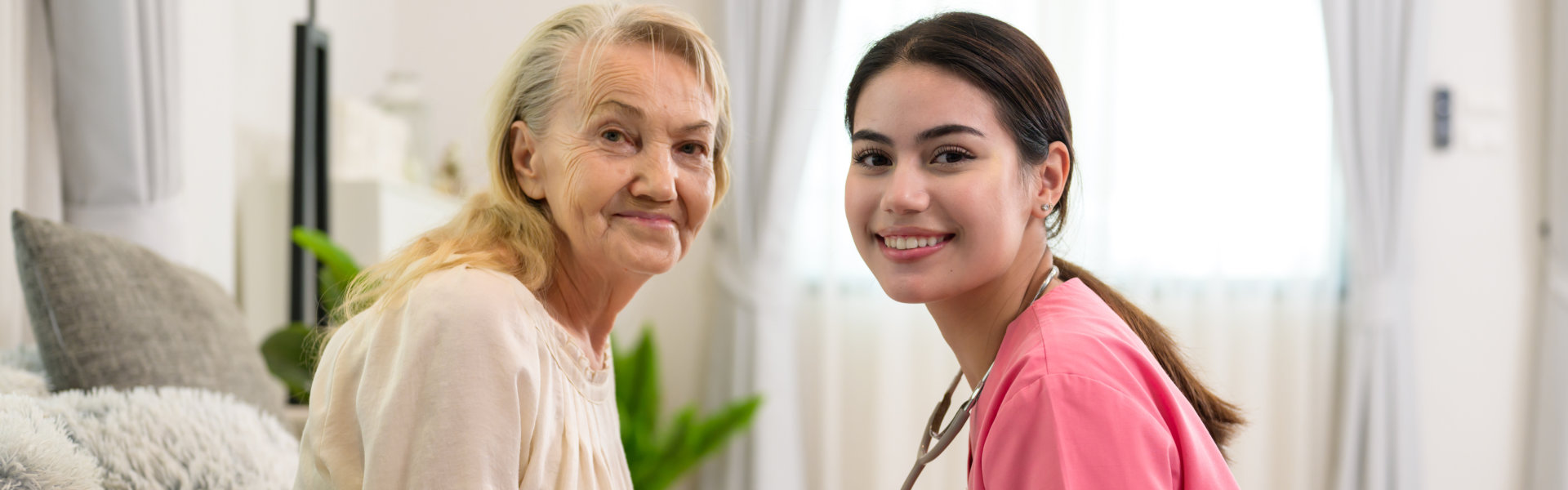 Happy senior woman talking with female caregiver in living room