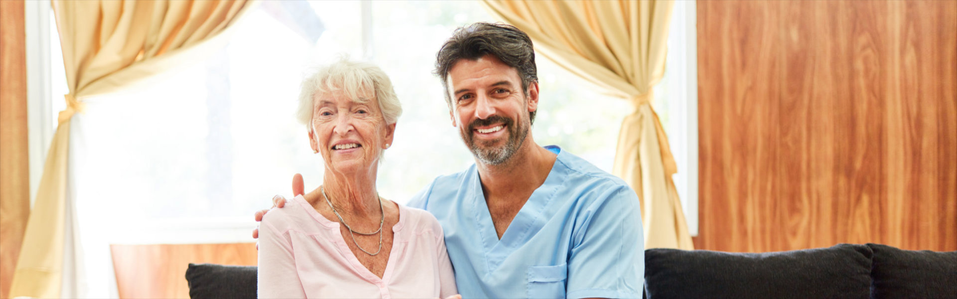 Smiling caregiver holding senior woman's hand